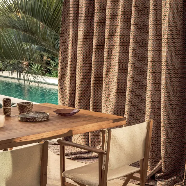 Textured outdoor curtains beside a shaded poolside dining area