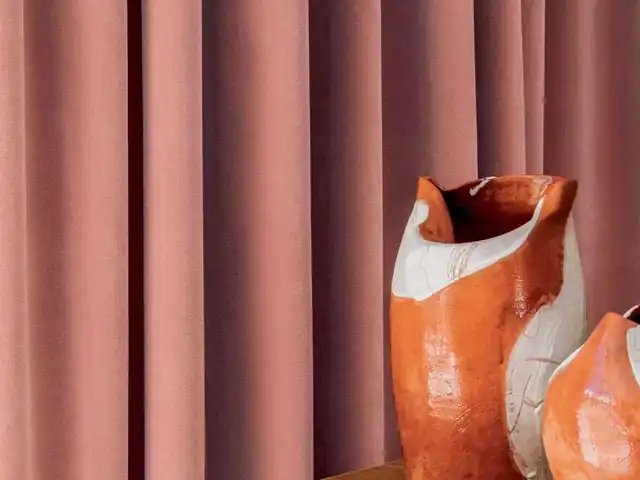 Dusty pink curtains beside orange ceramic vases