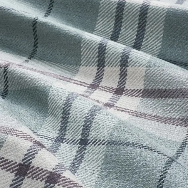 Softly coloured plaid upholstery fabric shown in close detail