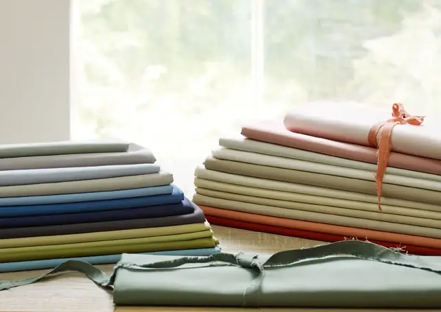 Plain satin fabrics arranged in a selection of soft and richly coloured shades