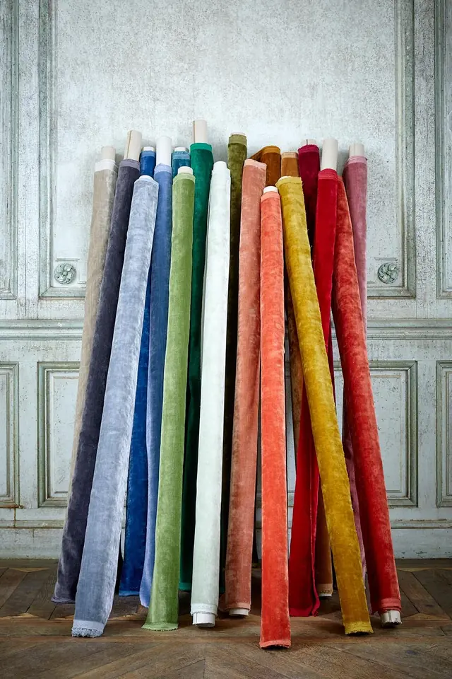 Rolls of plain velvet fabric in blue, green, pink, red and ochre colourways