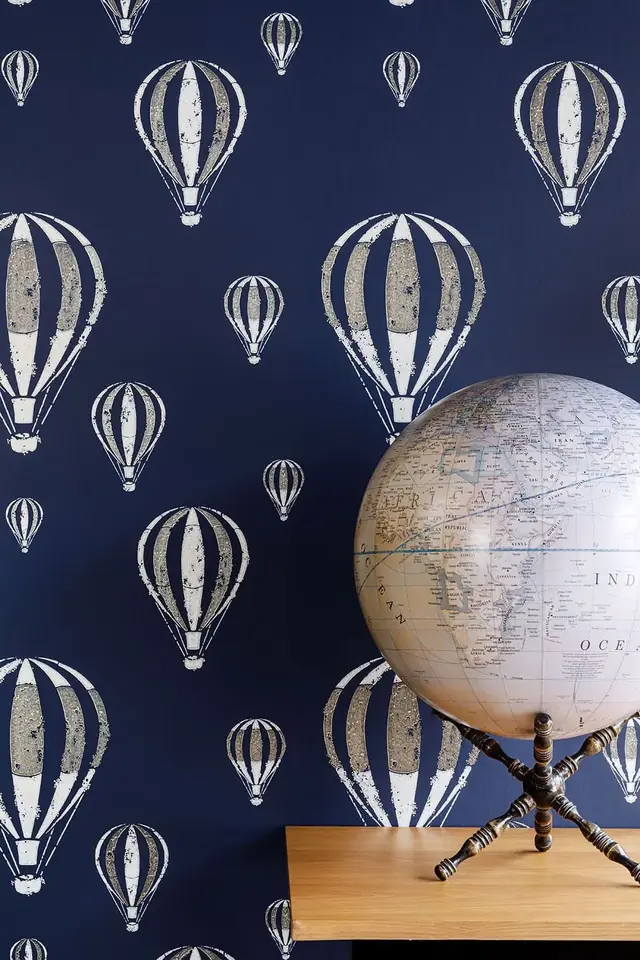 Hot-air balloon motifs repeating across dark blue wallpaper in a playful interior