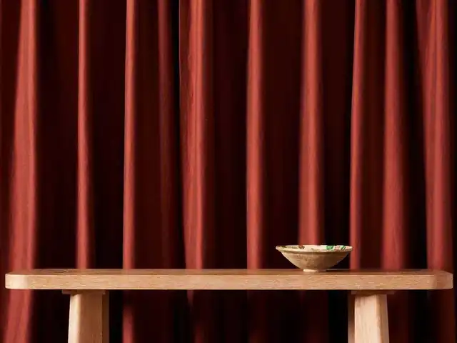 Deep red curtains behind a wooden table