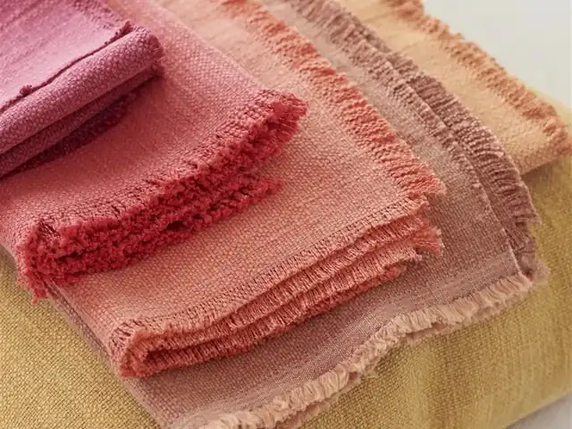 Layered red, rose and warm neutral fabric samples showing woven texture