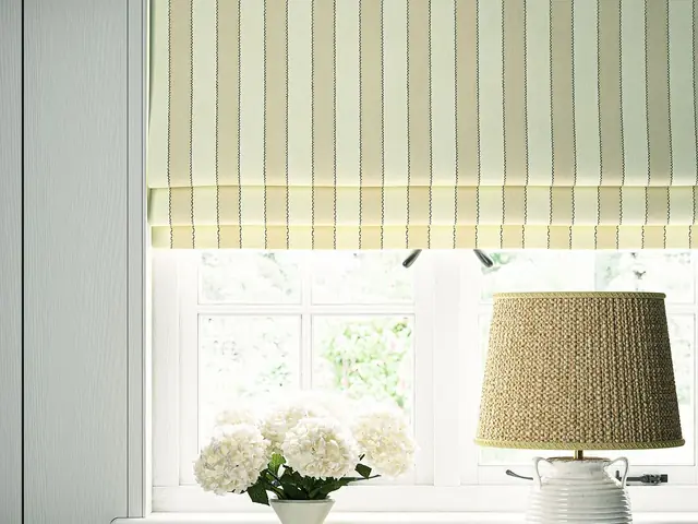 Cream striped Roman blind fitted above a window in a neutral interior