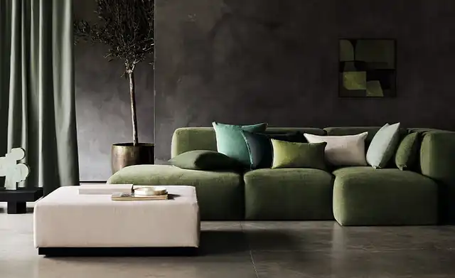 Romo Linara fabric on a green sofa and cushions beside plain curtains