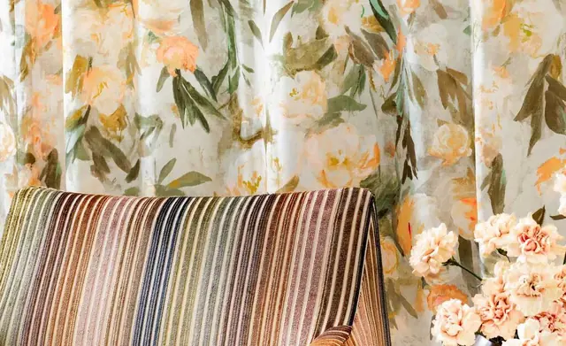 Layered Romo floral fabric, striped upholstery and patterned curtain in an interior setting