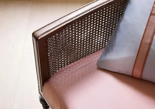 Pale pink satin upholstery fabric on a cane-backed chair with a coordinating cushion