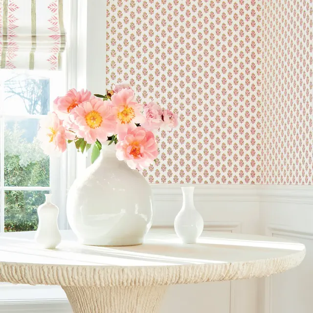 Small pink floral motifs repeating across a light wallpaper in a bright interior