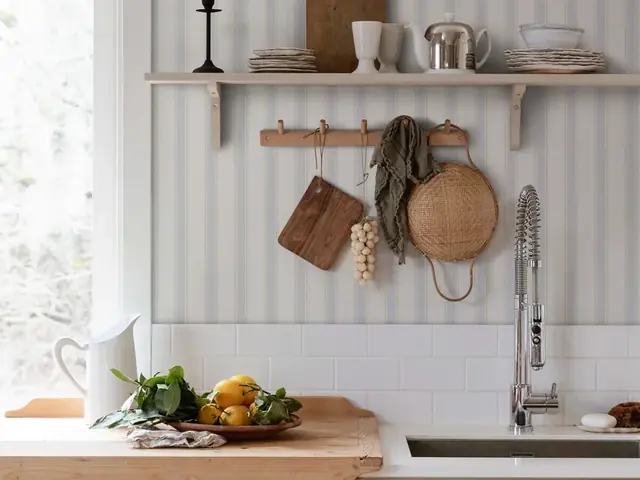 Soft striped wallpaper above pale kitchen cabinetry
