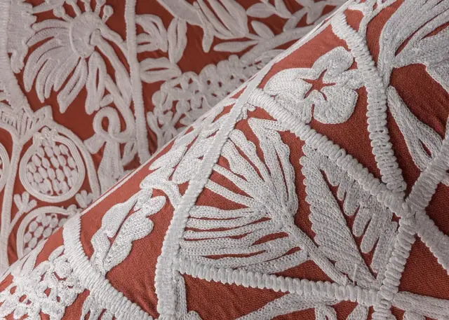 Coral textile wallcovering with raised white floral embroidery