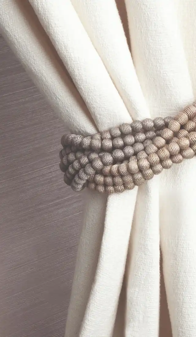 Neutral textured tieback holding back a cream curtain