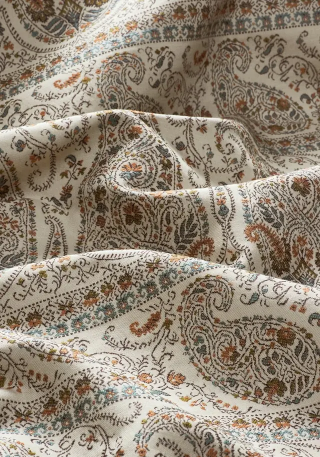 Close view of a traditional paisley fabric in cream, rust and blue