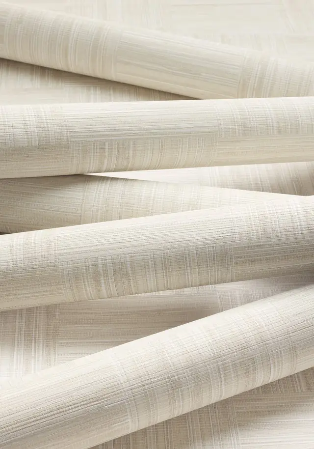 Cream wallpaper rolls showing woven texture and variation in neutral tones