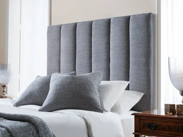 Tall vertically fluted upholstered headboard in grey fabric