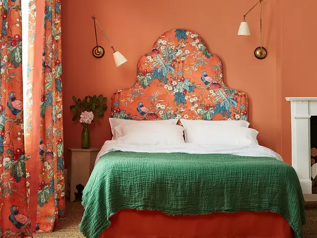 Upholstered shaped headboard in orange botanical fabric with coordinating curtains