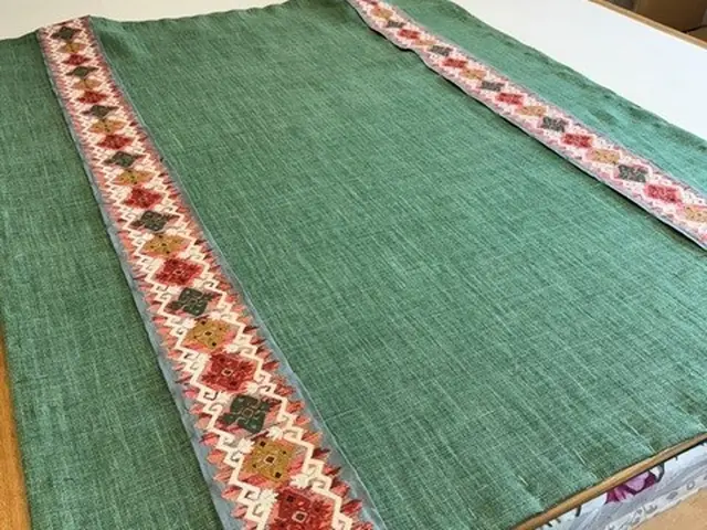 Green Roman blind with decorative contrast borders laid out in the TM Interiors workroom