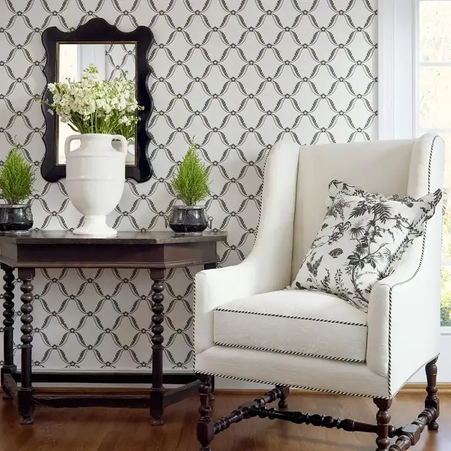 Black fern-like trellis wallpaper in a traditional sitting room with an upholstered armchair