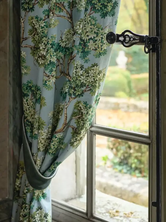 Pale blue curtain fabric patterned with flowering branches and green foliage