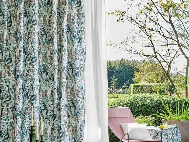 Blue-green botanical curtains beside an open doorway to a garden