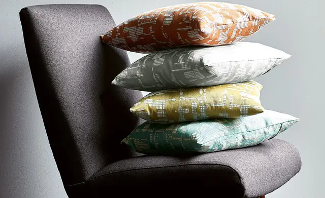 Contemporary chair with washable upholstery fabric and a stack of colourful cushions