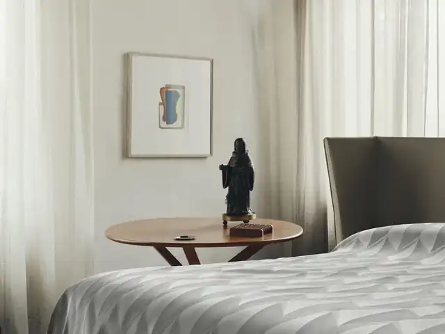 White curtains beside a bed with pale geometric-patterned fabric