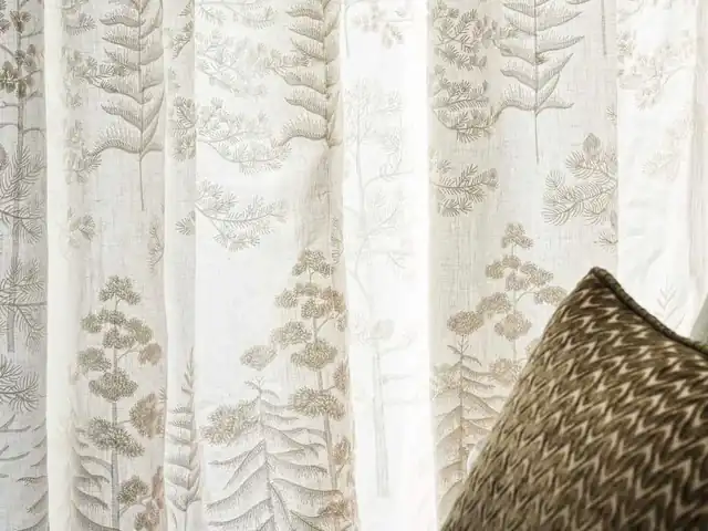 Light botanical motifs across a white sheer curtain