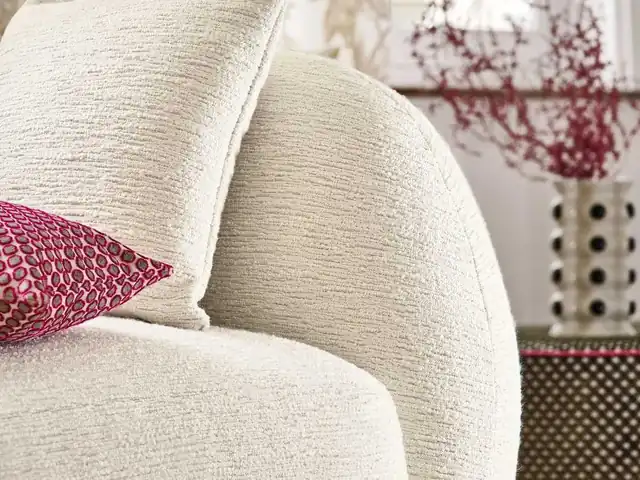 Close-up of softly textured white upholstery with pale and pink cushions