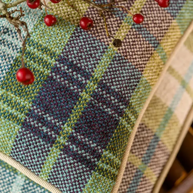 Close view of colourful woven check upholstery with piped edges