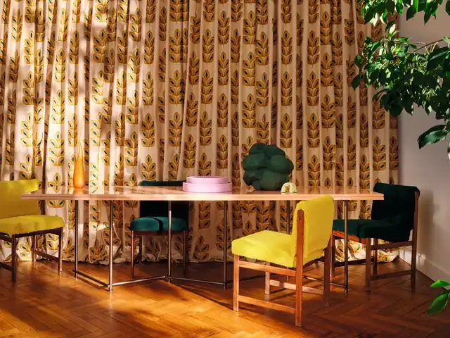 Yellow and green dining chairs beside patterned curtains in a sunlit room