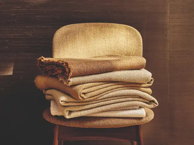 Folded golden yellow and neutral textured fabrics stacked on a chair