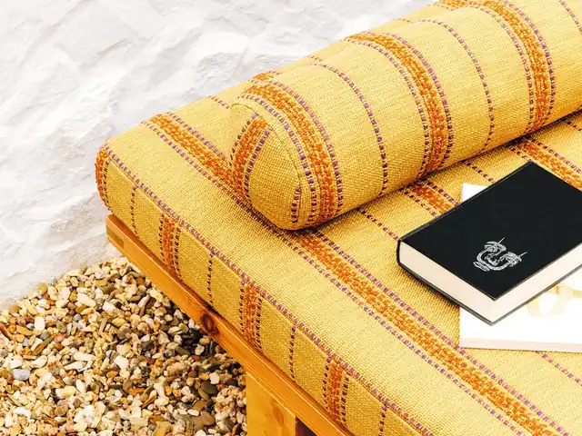 Yellow striped fabric covering a bench cushion and cylindrical bolster