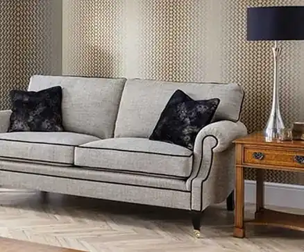 Grey upholstered sofa with dark cushions beside a wooden side table