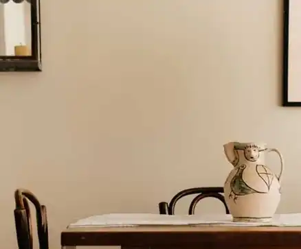 Warm beige painted dining room wall with a ceramic jug on a wooden table