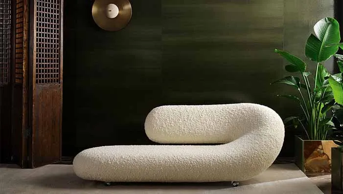 An image of boucle fabric upholstered on a chair, highlighting its textured, looped surface and cozy appearance.
