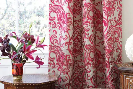 Curtains with red spiral pattern next to a table with a plant