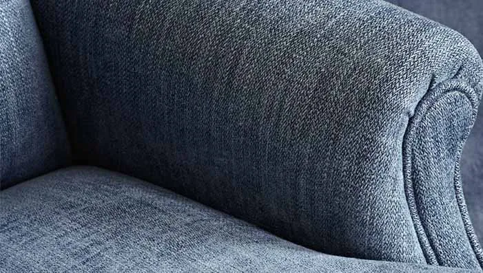 Close-up of a blue herringbone-patterned fabric on an armchair, showcasing the texture and pattern. Ideal for adding a touch of classic style to upholstery.
