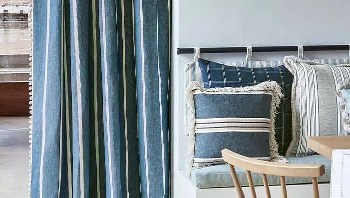 A cozy nook with striped curtains and cushions in shades of blue and white, creating a relaxed and inviting atmosphere.