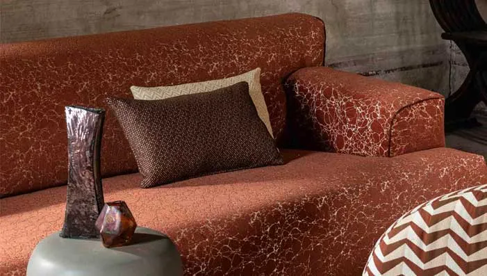 A close-up view of vibrant green and blue cushions stacked together on a sofa, highlighting upholstery fabric.